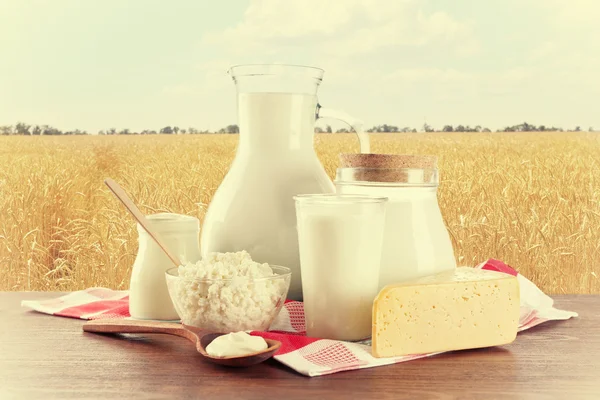 Milchprodukte auf Holztisch vor Feldhintergrund — Stockfoto