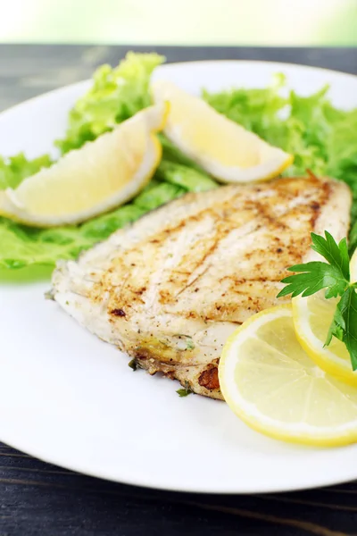 Prato de filé de peixe com alface e limão na mesa close up — Fotografia de Stock