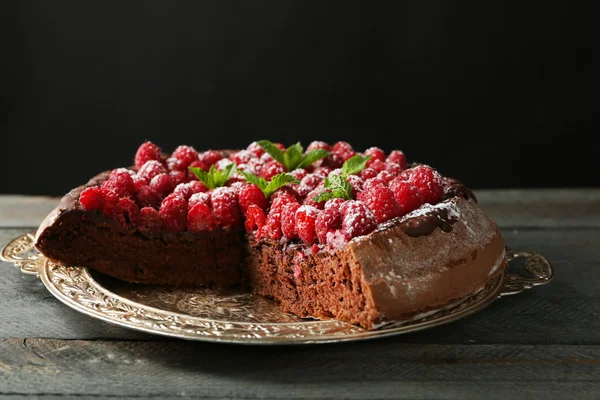 Торт с шоколадной глазурью и малиной на подносе на темном фоне — стоковое фото