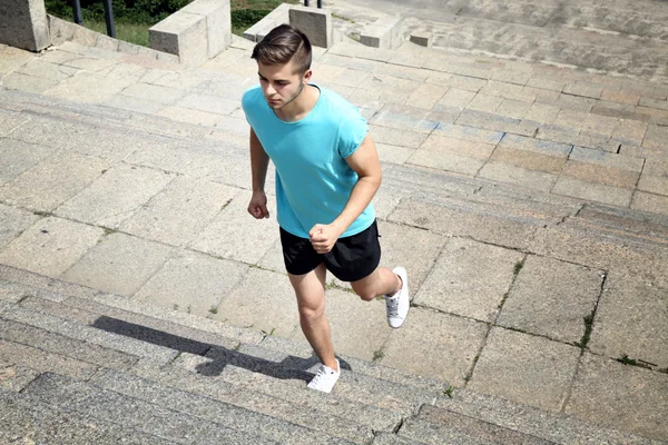 Ung man jogging på trappor utomhus — Stockfoto