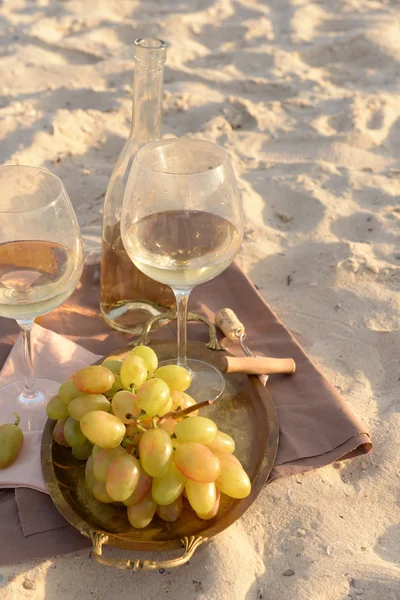 Composizione romantica di vino bianco e uva sulla spiaggia sabbiosa — Foto Stock
