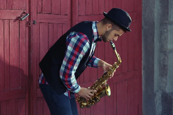 Knappe man in hat speelt sax — Stockfoto