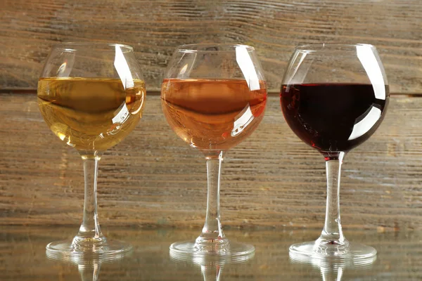 Brýle s bílou, rose a červené víno na dřevěné pozadí — Stock fotografie