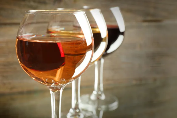 Óculos com vinho branco, rosa e tinto sobre fundo de madeira, close-up — Fotografia de Stock