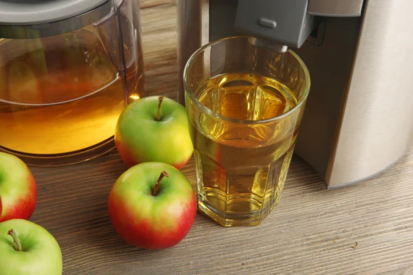 Ekstraktor jus nirkarat dengan apel dan segelas jus pada latar belakang kayu, tutup — Stok Foto