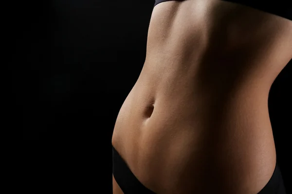 Magro corpo feminino em lingerie preta agradável no fundo escuro — Fotografia de Stock