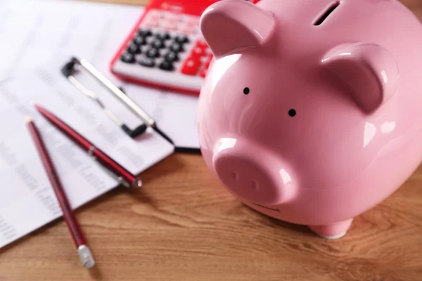 Pig moneybox and calculating equipment on desk closeup — Stock Photo, Image