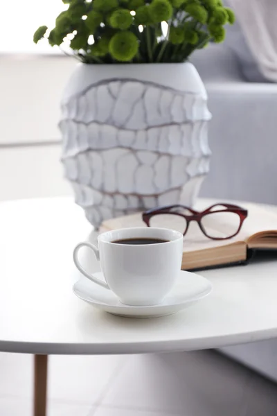 Cup of coffee with book on table in room — Stock Photo, Image