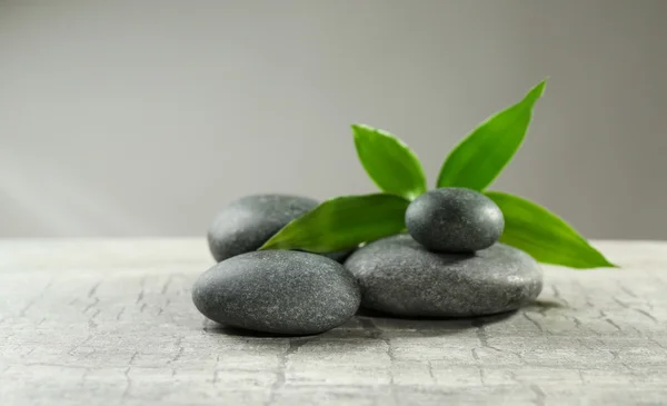 Composition of pebbles with leaf on the table against grey background — Stock Photo, Image
