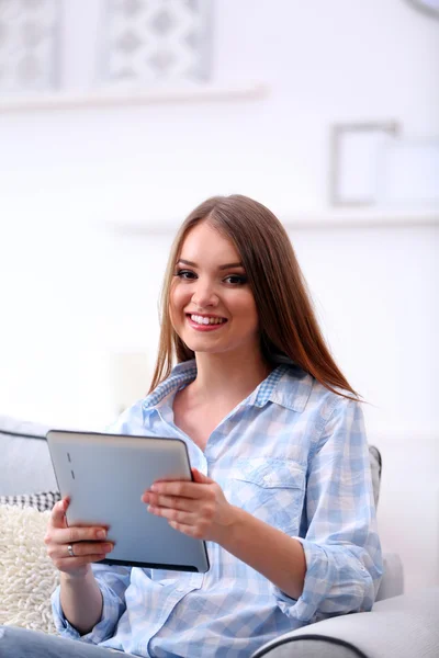 Hezká žena sedí na pohovce s tabletem — Stock fotografie