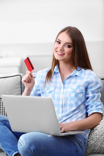 Jonge mooie vrouw met laptop en een creditcard bij u thuis — Stockfoto