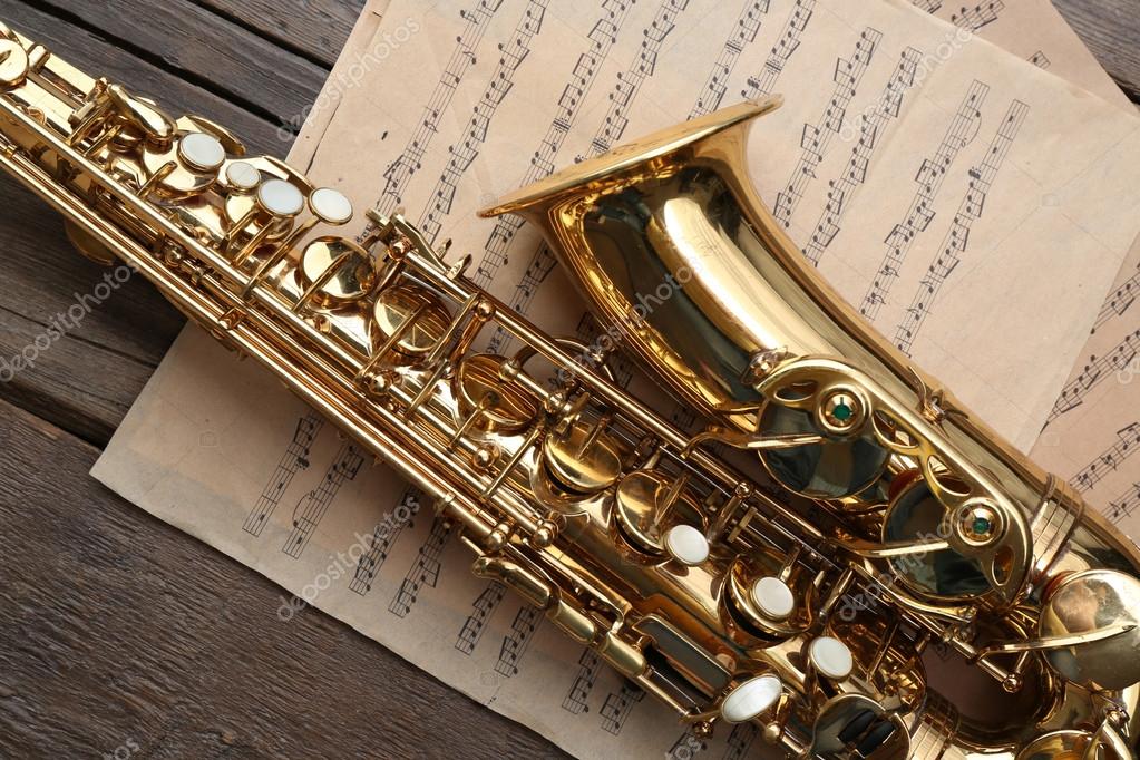 Beautiful golden saxophone with musical notes on wooden background