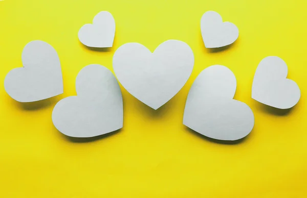 Paper hearts on yellow paper background, close-up — Stock Photo, Image