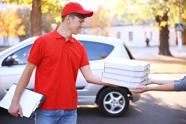 ピザ配達の車の近くにピザの箱を保持しています。 — ストック写真