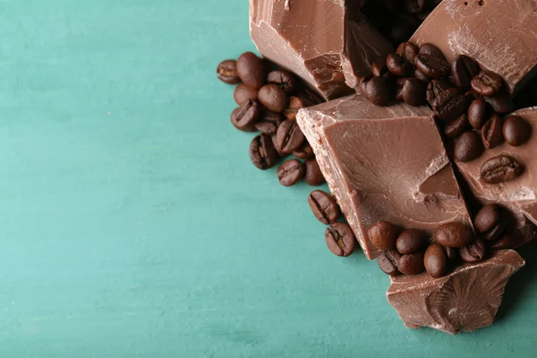 Mjölk choklad bitar och kaffe korn på färg trä bakgrund — Stockfoto