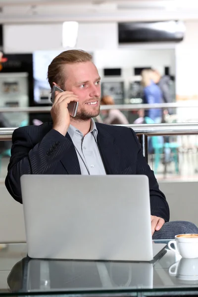 Joven empresario atractivo almorzando y trabajando en una cafetería — Foto de Stock