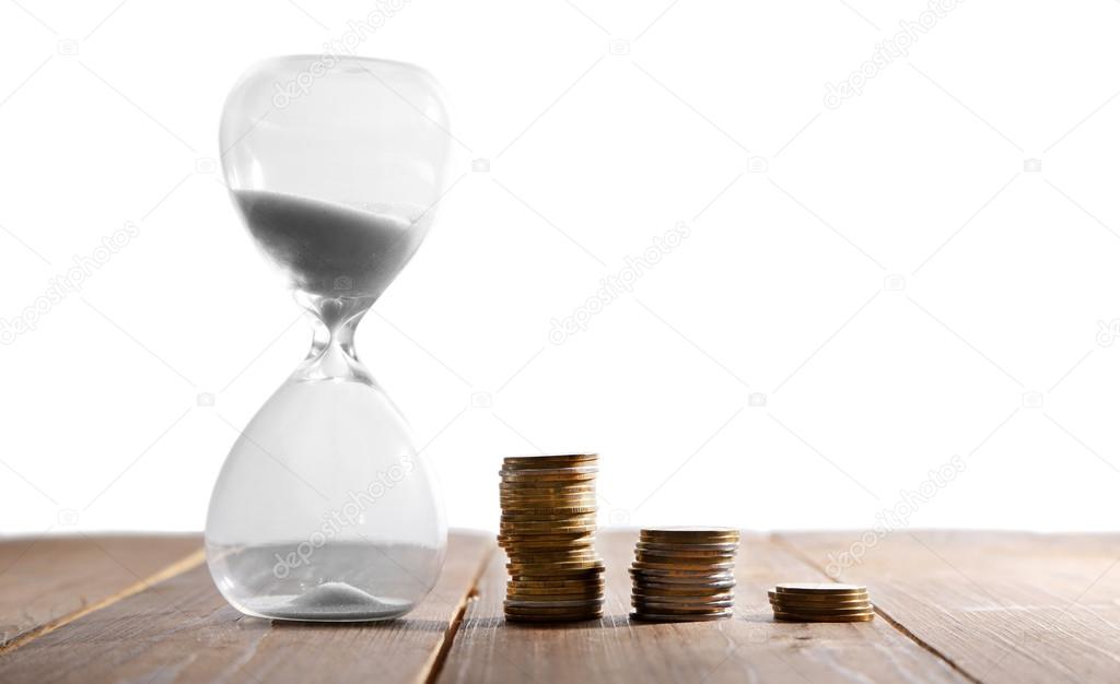 Hourglass with coins on wooden table on white background