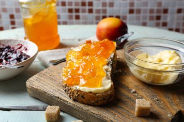 Lezzetli reçel kavanoz ve çanaklar, tereyağı, taze ekmek ve kraker mavi ahşap zemin üzerine