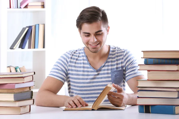 Молодой человек читает книгу за столом — стоковое фото