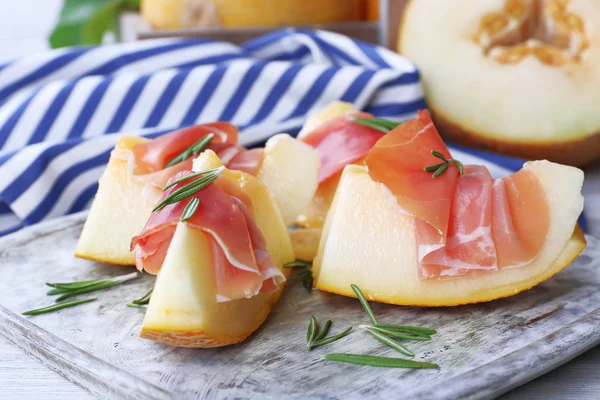 Melon with prosciutto of Parma ham on wooden table, closeup — Stock Photo, Image