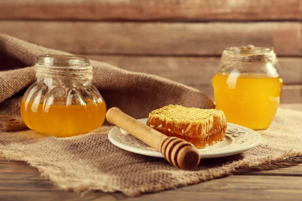 Krukor med honung och honeycomb med skopa på säckväv — Stockfoto