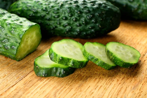 Gesneden komkommers op houten achtergrond — Stockfoto