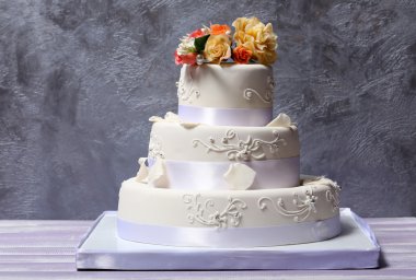 Düğün pastası gri arka plan üzerine çiçeklerle dekore edilmiş