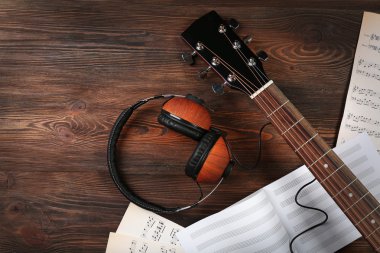 Gitar earphones ve ahşap arka plan üzerine müzik yaprak ile