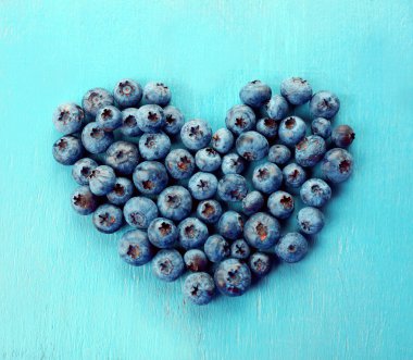 Bilberries eski ahşap arka plan üzerinde kalp şeklinde