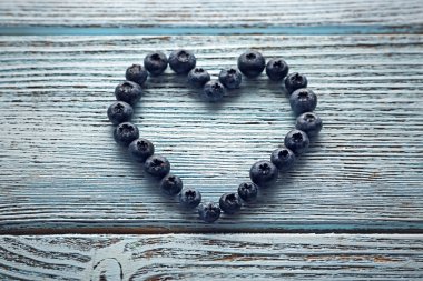 Bilberries eski ahşap arka plan üzerinde kalp şeklinde