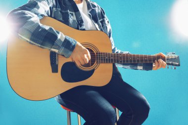 Müzisyen gitar çalan ve vokalde üzerinde mavi arka plan, yakın çekim