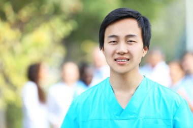 Tıbbi işçilerin odaklanmamış grup karşı duran genç gülümseyen doktor