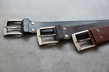 Leather belts with buckles on gray background clipart