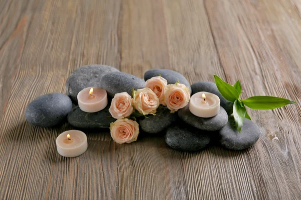 Spa-skład świece, kwiaty i kamienie na brązowym tle drewniane — Zdjęcie stockowe