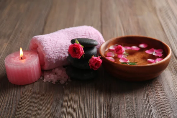 Spa sammansättningen av en handduk, salt, blommor och stenar, på trä bakgrund — Stockfoto