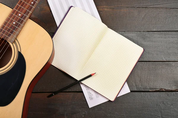 Gitarre und Notenblätter auf Holzgrund — Stockfoto