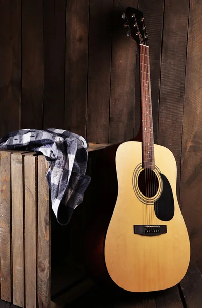 Guitarra y camisa izquierda en caja sobre fondo de pared de madera — Foto de Stock