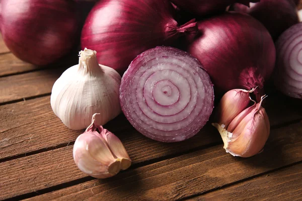 Fresh red onions with garlic on wooden background — Stock Photo, Image