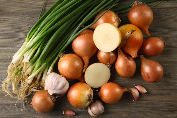 Cebollas frescas diferentes con ajo sobre fondo de madera — Foto de Stock