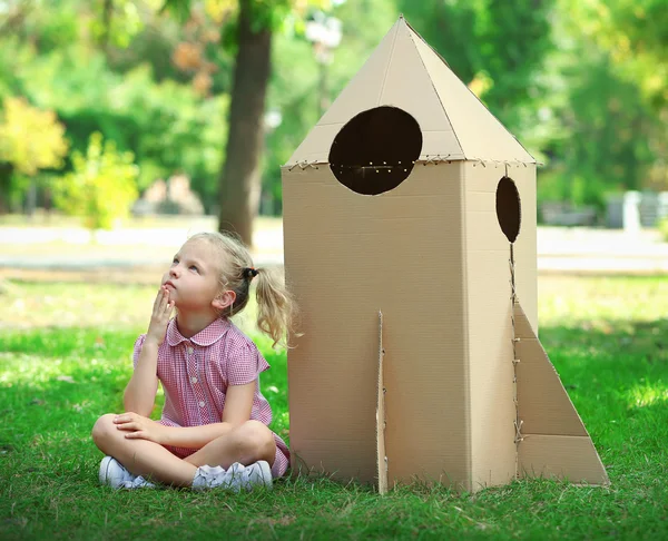 Девочка рядом с картонной ракетой — стоковое фото