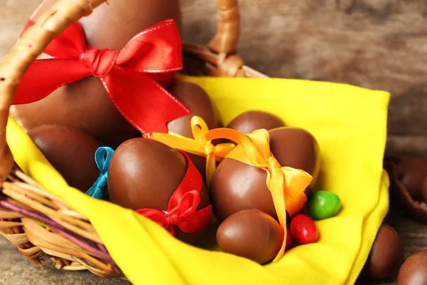 Ovos de Páscoa de chocolate em cesta no fundo de madeira — Fotografia de Stock