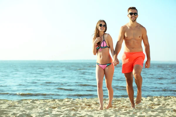Счастливая пара держится за руки на пляже — стоковое фото