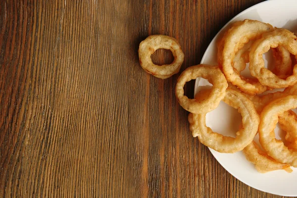 Chips ringen op plaat op houten achtergrond — Stockfoto