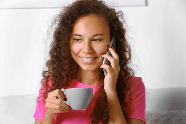 Ritratto ravvicinato di giovane donna in abito rosa che parla al cellulare con una tazza di caffè — Foto Stock