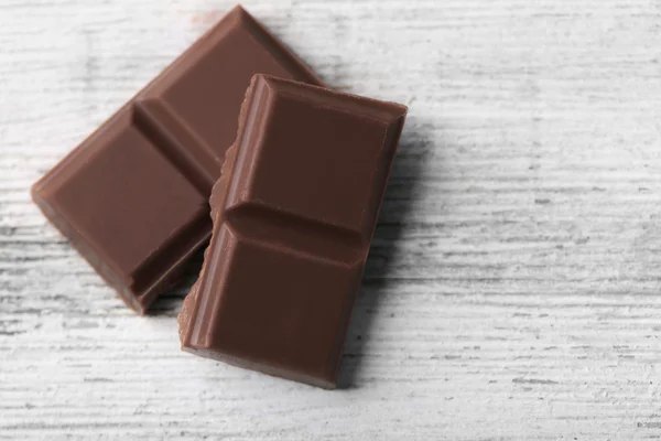 木の色の背景に黒のチョコレートの部分 — ストック写真