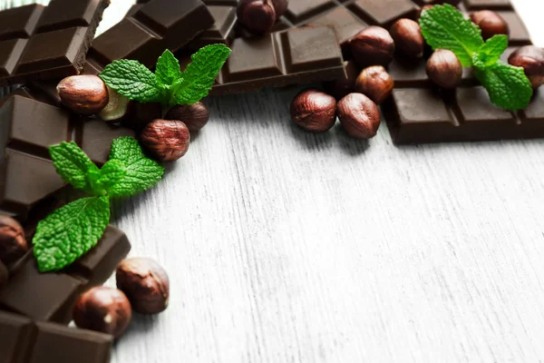 Choklad bitar med nötter på färg trä bakgrund — Stockfoto