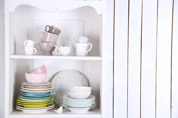 Different clean dishes on wooden shelves — Stock Photo, Image