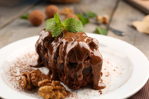 Un pedazo de pastel de chocolate con nuez y menta en la mesa, primer plano — Foto de Stock