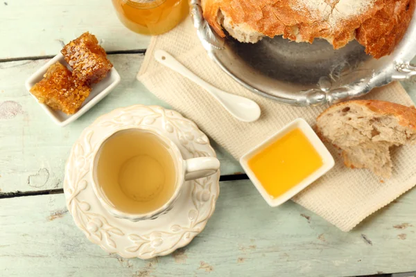 Peigne en nid d'abeille, bol avec miel, tasse avec tisane sur fond en bois de couleur — Photo