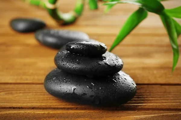 Spa stones and bamboo branch on wooden background — Stock Photo, Image